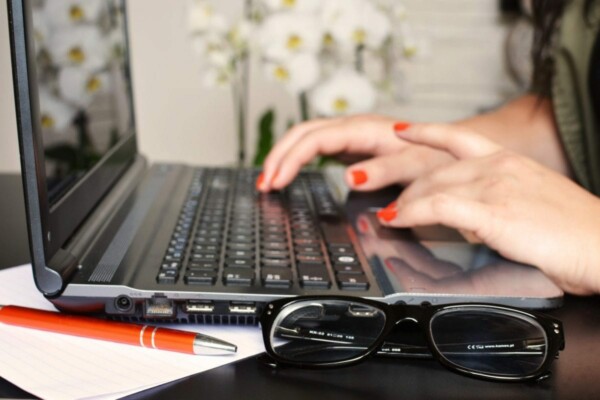 The alt tag for the image located at the provided URL could be: "Professional woman typing on a laptop computer in a modern office environment. - PSM Marketing